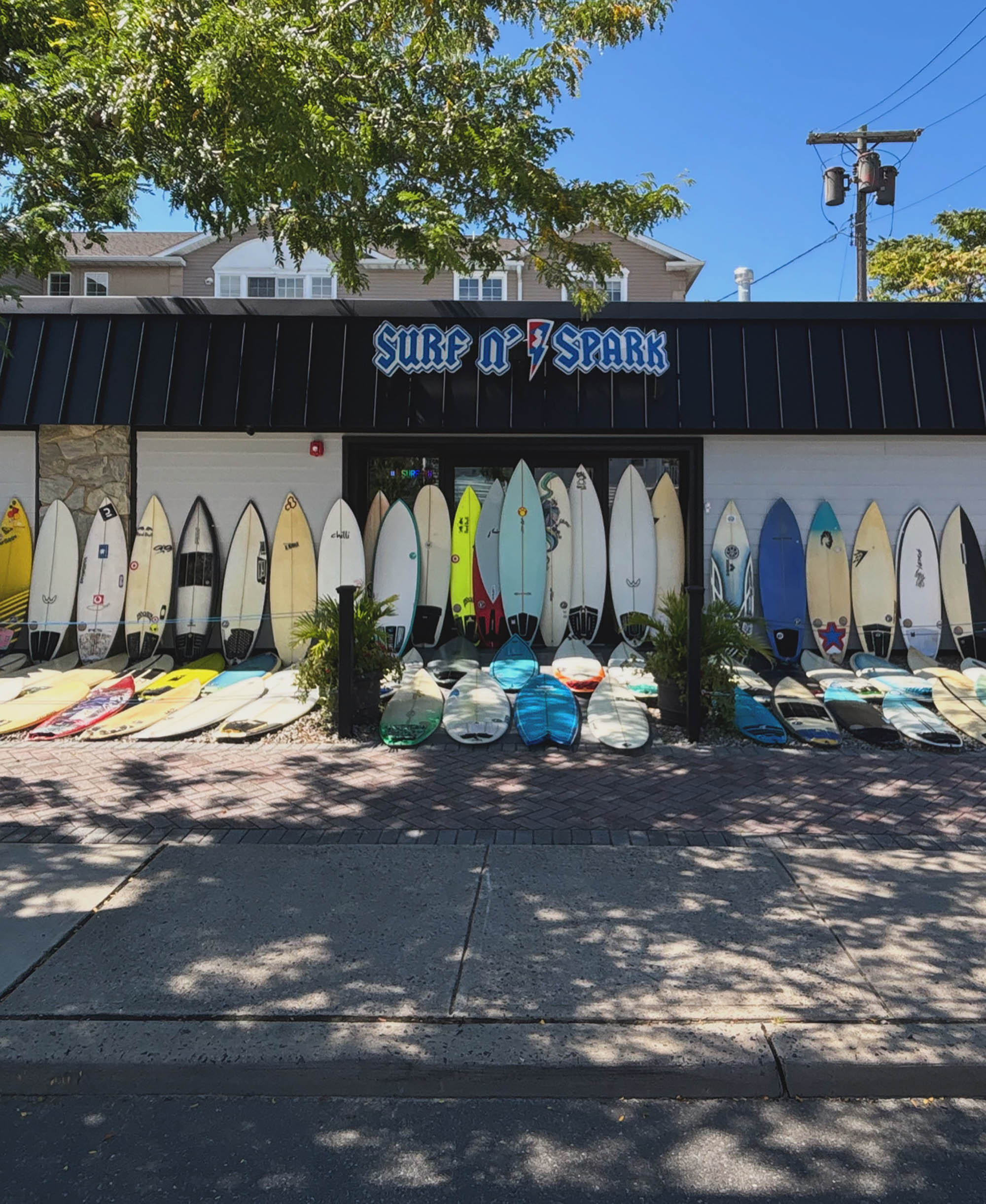 Surfboard shop with surfboards lined up outside on a sunny day.